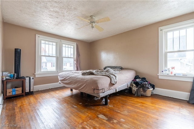 bedroom with ceiling fan, radiator heating unit, wood-type flooring, and a textured ceiling