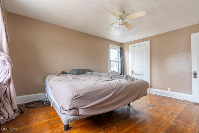 bedroom featuring ceiling fan, hardwood / wood-style floors, and a textured ceiling