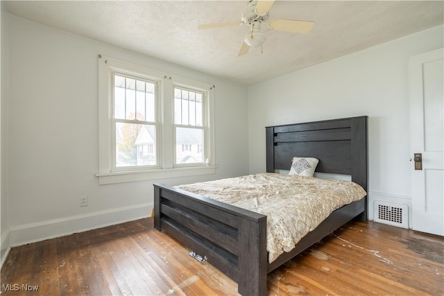 bedroom featuring a textured ceiling, ceiling fan, and dark wood-type flooring