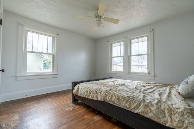 bedroom with ceiling fan, dark hardwood / wood-style flooring, and a textured ceiling