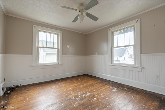 unfurnished room with hardwood / wood-style floors, ceiling fan, crown molding, and a wealth of natural light