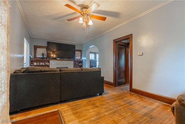 living room with hardwood / wood-style floors, a textured ceiling, ceiling fan, and ornamental molding