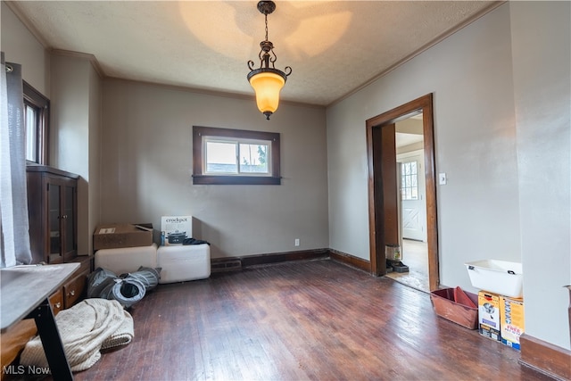 interior space with dark wood-type flooring, a textured ceiling, and ornamental molding