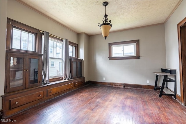 unfurnished room with plenty of natural light, baseboards, a textured ceiling, and dark wood finished floors