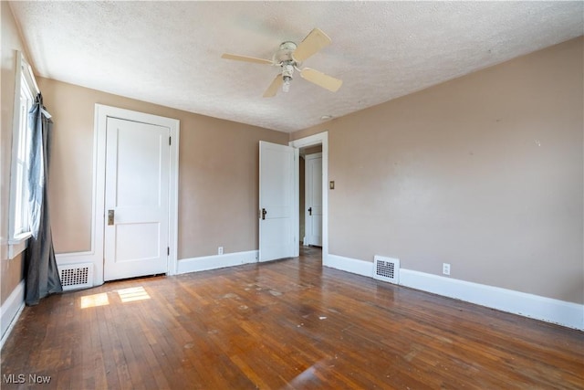 unfurnished bedroom with a ceiling fan, a textured ceiling, wood-type flooring, baseboards, and visible vents