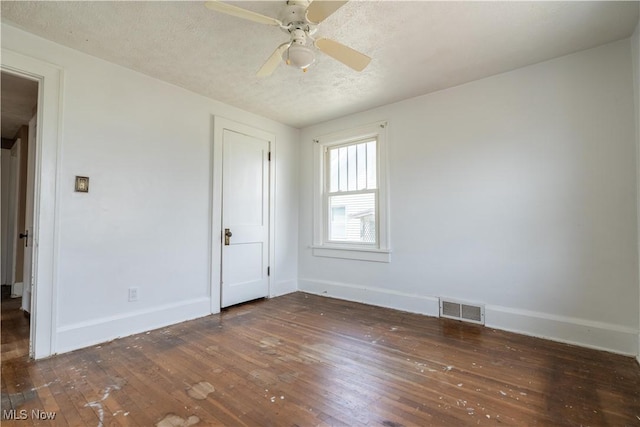 spare room with baseboards, visible vents, a textured ceiling, and wood-type flooring