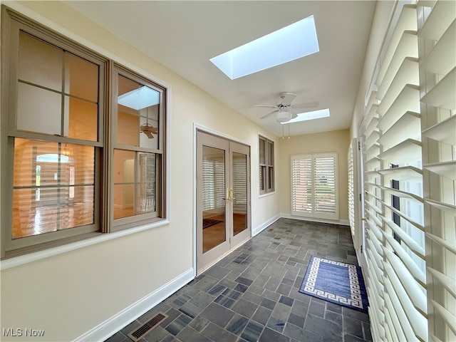 unfurnished sunroom featuring a skylight, ceiling fan, and french doors