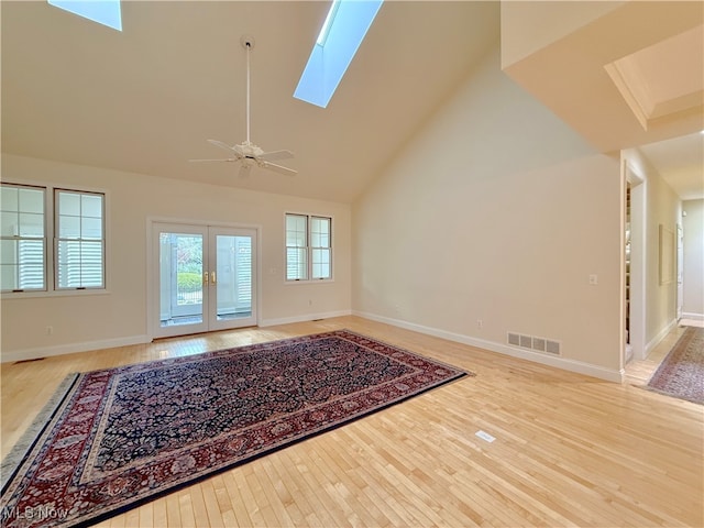 unfurnished living room with ceiling fan, french doors, high vaulted ceiling, and light hardwood / wood-style flooring