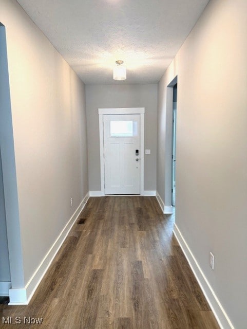 doorway to outside featuring dark hardwood / wood-style flooring and a textured ceiling