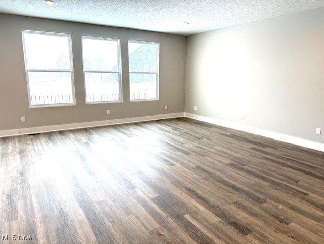 spare room featuring dark wood-type flooring and a textured ceiling