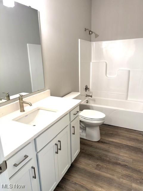 full bathroom with washtub / shower combination, wood-type flooring, toilet, and vanity