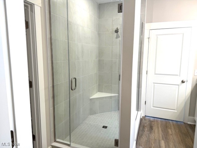 bathroom with wood-type flooring and an enclosed shower