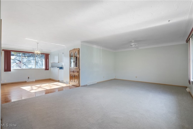 unfurnished living room featuring hardwood / wood-style floors, ceiling fan with notable chandelier, and crown molding