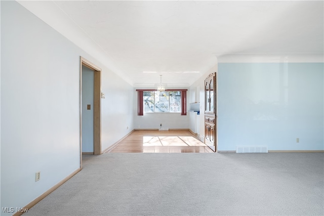 unfurnished living room with light carpet and a chandelier