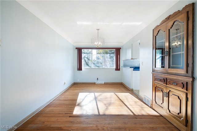 unfurnished dining area featuring a chandelier and light hardwood / wood-style flooring