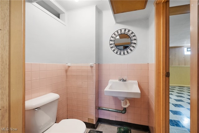 bathroom with crown molding, sink, tile walls, and toilet