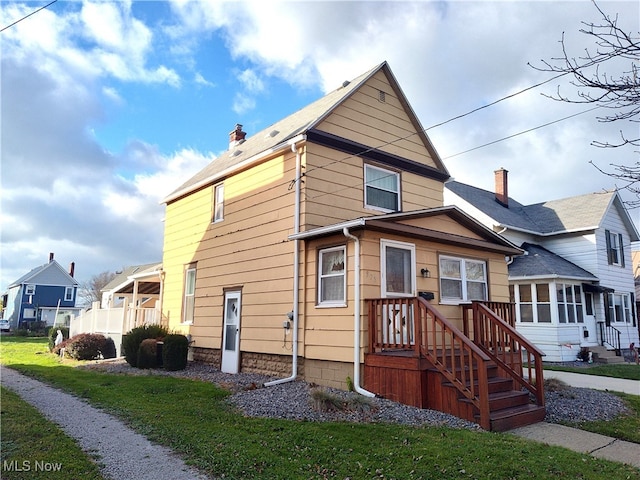 view of front of home with a sunroom and a front lawn