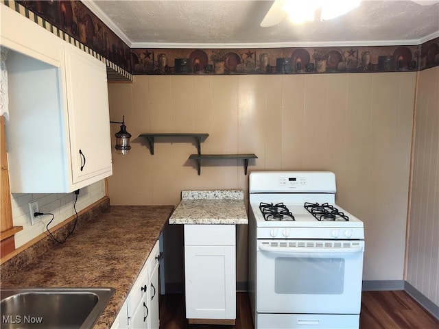 975 Broad St, Conneaut, OH 44030 - kitchen featuring white gas range, white cabinets, dark wood-type flooring, and tasteful backsplash
