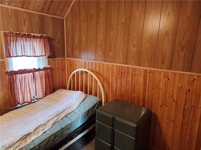 bedroom with carpet flooring and wood walls