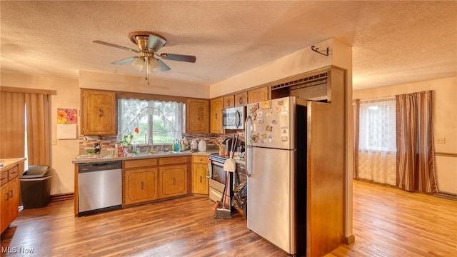 kitchen with hardwood / wood-style flooring, ceiling fan, stainless steel appliances, and a textured ceiling