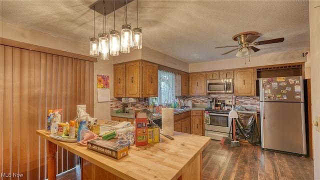 kitchen with pendant lighting, backsplash, dark hardwood / wood-style floors, a textured ceiling, and stainless steel appliances