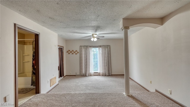 carpeted spare room with a textured ceiling, decorative columns, and ceiling fan