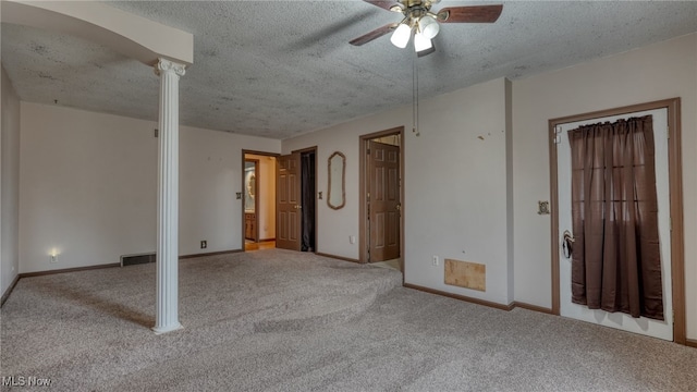 carpeted empty room with ornate columns, ceiling fan, and a textured ceiling