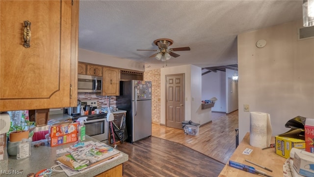 kitchen with hardwood / wood-style floors, ceiling fan, stainless steel appliances, and a textured ceiling