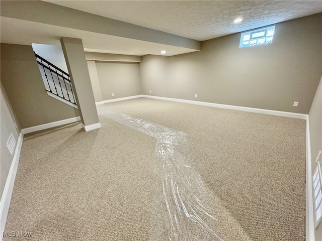 basement featuring carpet flooring and a textured ceiling