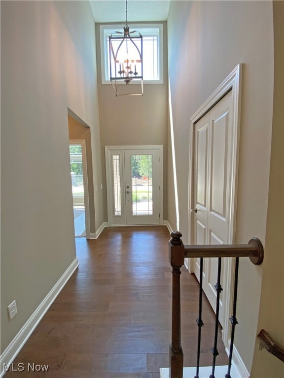 entrance foyer with a chandelier, a high ceiling, dark wood-type flooring, and a healthy amount of sunlight