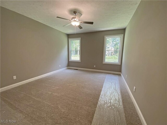 carpeted empty room featuring ceiling fan and a textured ceiling