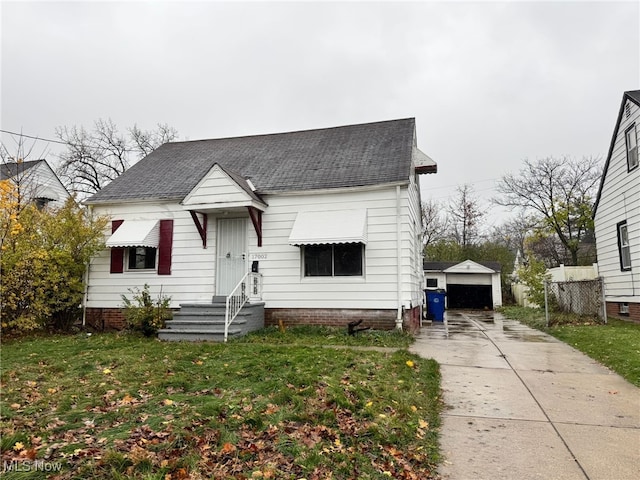 bungalow featuring an outdoor structure, a front yard, a detached garage, and a shingled roof