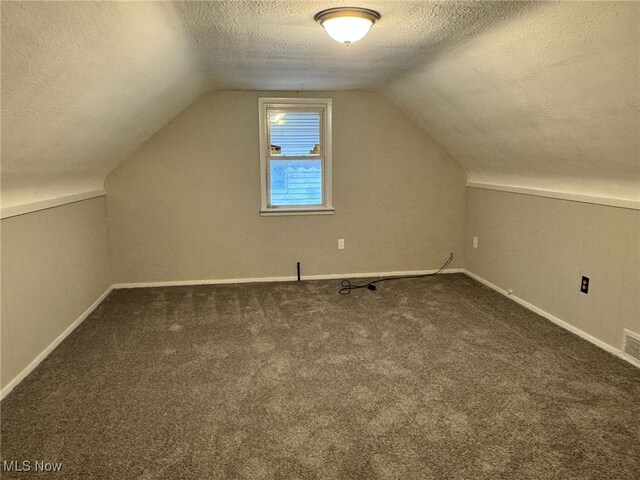 bonus room featuring dark colored carpet, a textured ceiling, and vaulted ceiling