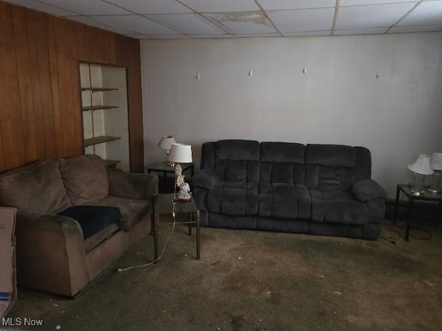 living room featuring a paneled ceiling and wooden walls