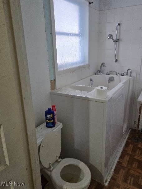 bathroom with parquet floors, toilet, and a bathtub