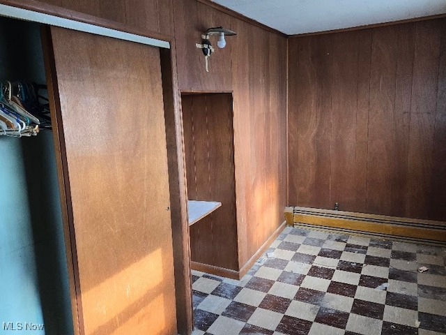 interior space with a baseboard radiator and wood walls