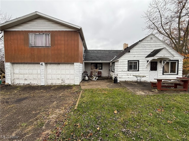 rear view of house featuring a lawn and a garage