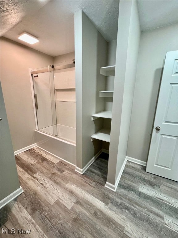 bathroom with wood-type flooring, a textured ceiling, and shower / tub combination