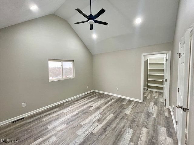 unfurnished bedroom with lofted ceiling, a walk in closet, light hardwood / wood-style flooring, ceiling fan, and a closet