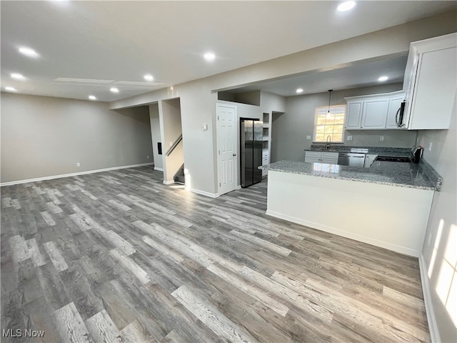 kitchen with light stone countertops, appliances with stainless steel finishes, light hardwood / wood-style floors, and white cabinetry