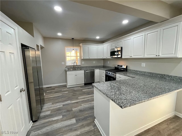 kitchen featuring kitchen peninsula, appliances with stainless steel finishes, sink, white cabinetry, and hanging light fixtures