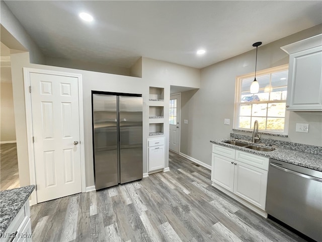 kitchen with white cabinetry, sink, stainless steel appliances, light hardwood / wood-style flooring, and stone countertops