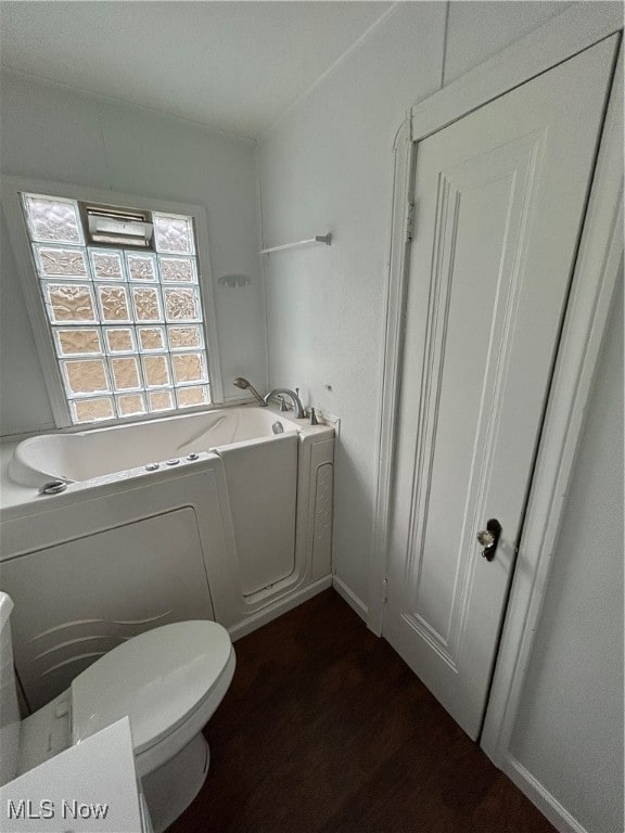 bathroom with toilet, wood-type flooring, and a bath