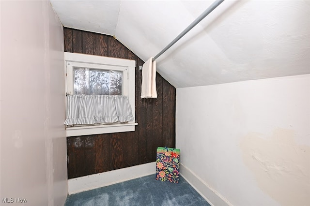 additional living space with carpet floors, lofted ceiling, and wood walls