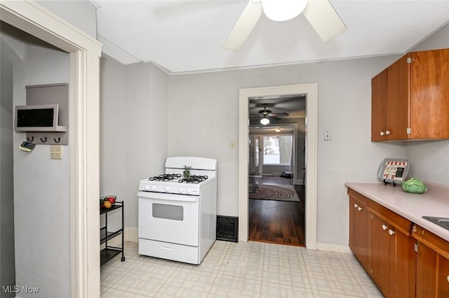 kitchen with light wood-type flooring, ceiling fan, and gas range gas stove