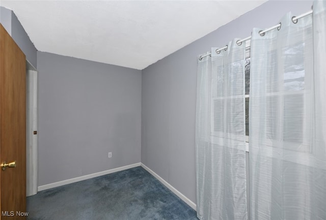 unfurnished room with dark colored carpet