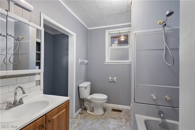 bathroom featuring vanity, toilet, tile walls, and ornamental molding