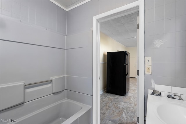 bathroom featuring a washtub, vanity, and tile walls