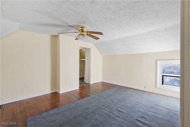 additional living space featuring a textured ceiling, lofted ceiling, and dark hardwood / wood-style floors