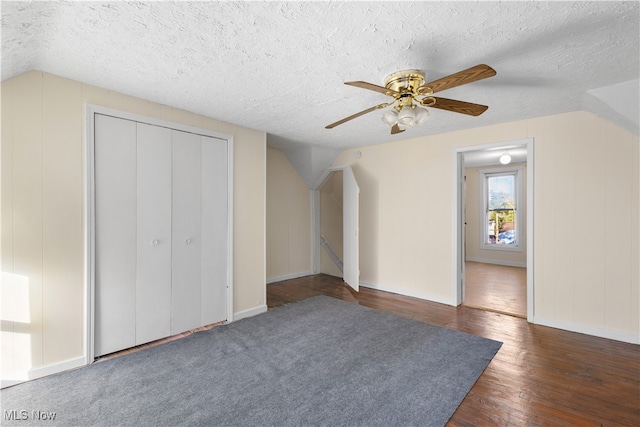 additional living space with ceiling fan, dark hardwood / wood-style flooring, a textured ceiling, and vaulted ceiling